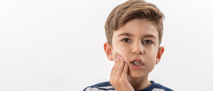 a young boy holding his cheek